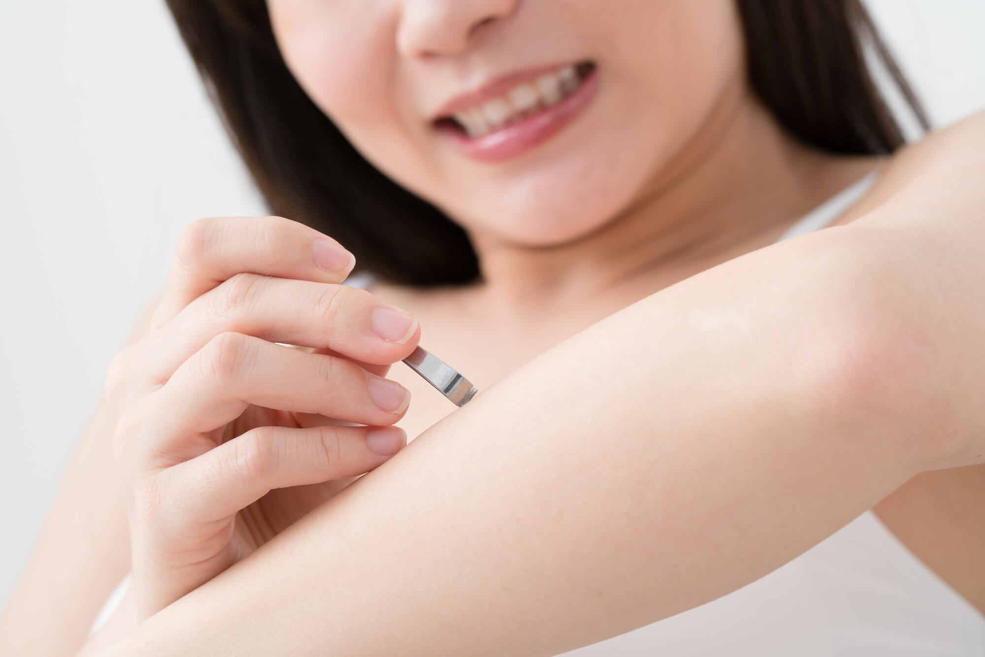 ピンセットで腕の毛を抜く女性