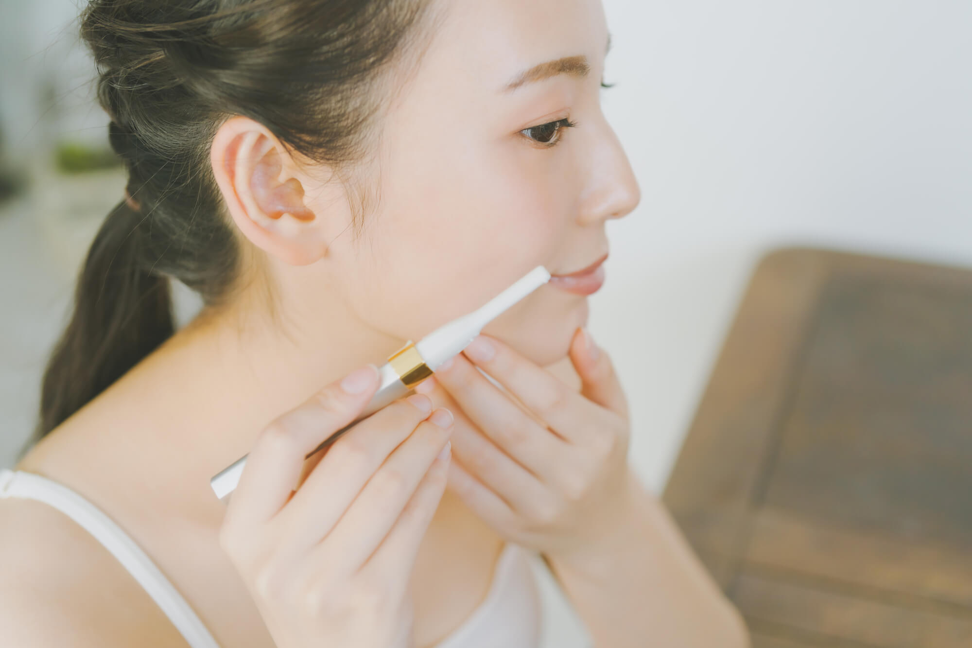 電動フェイスシェーバーで産毛を剃る女性
